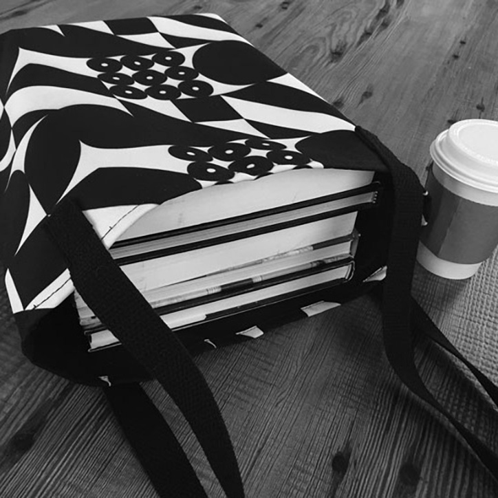 Image of black and white tote bag on old wooden table with coffee cup.