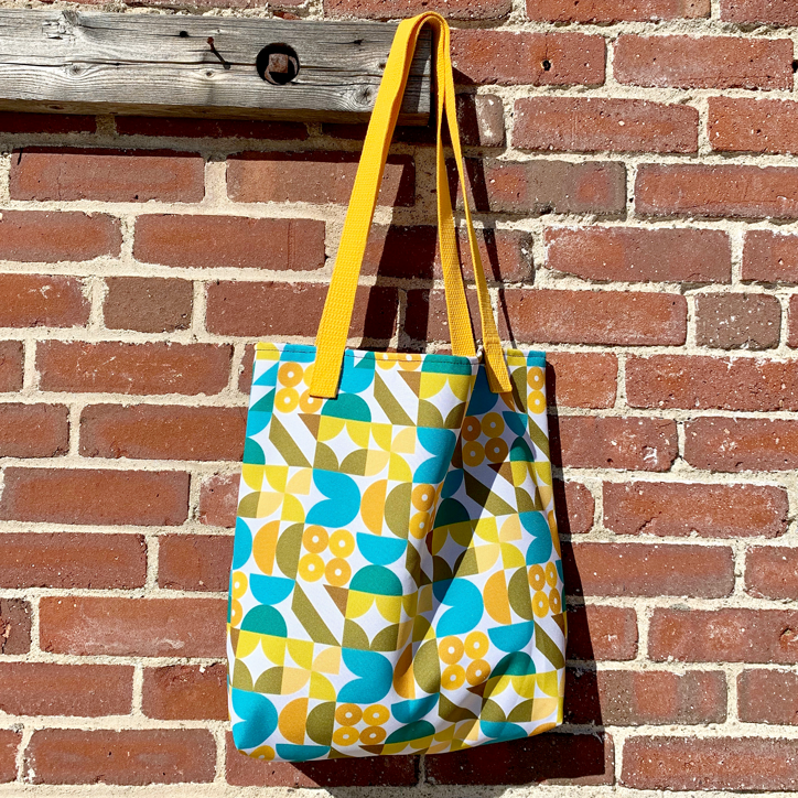 Image of colorful tote bag against a brick wall.